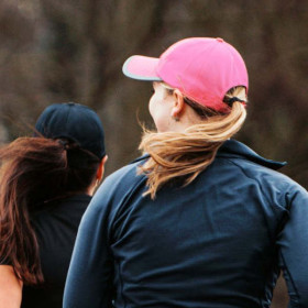 Frau mit Baseballmütze mit Mesh-Einsatz und reflektierender Randzone am Schirm. Farbe Pink.